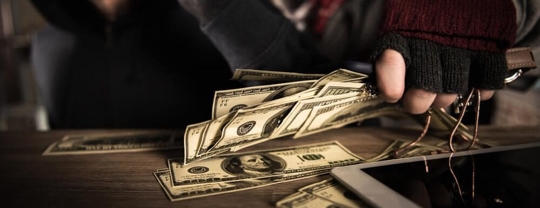 burglar's hand holding money and jewelry