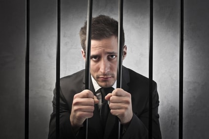 man in suit behind jail bars