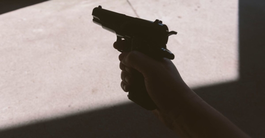 Man holding gun in building doorway.