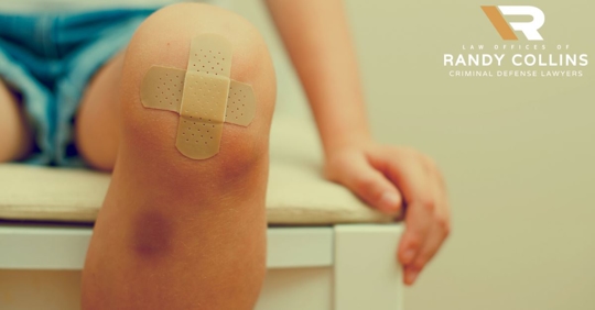 person sitting on seat with bruised knee and bandaids
